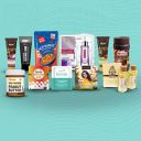 Mojo Box gift combo includes Lemon green tea, Hair Shampoos, Face Mask + Scrub, Ayurvedic body oil, Hibiscus infusion bag, Serum Sheet Mask, Schezwan Cooking Sauce, Peanut Butter and Foxtale Cleanser...